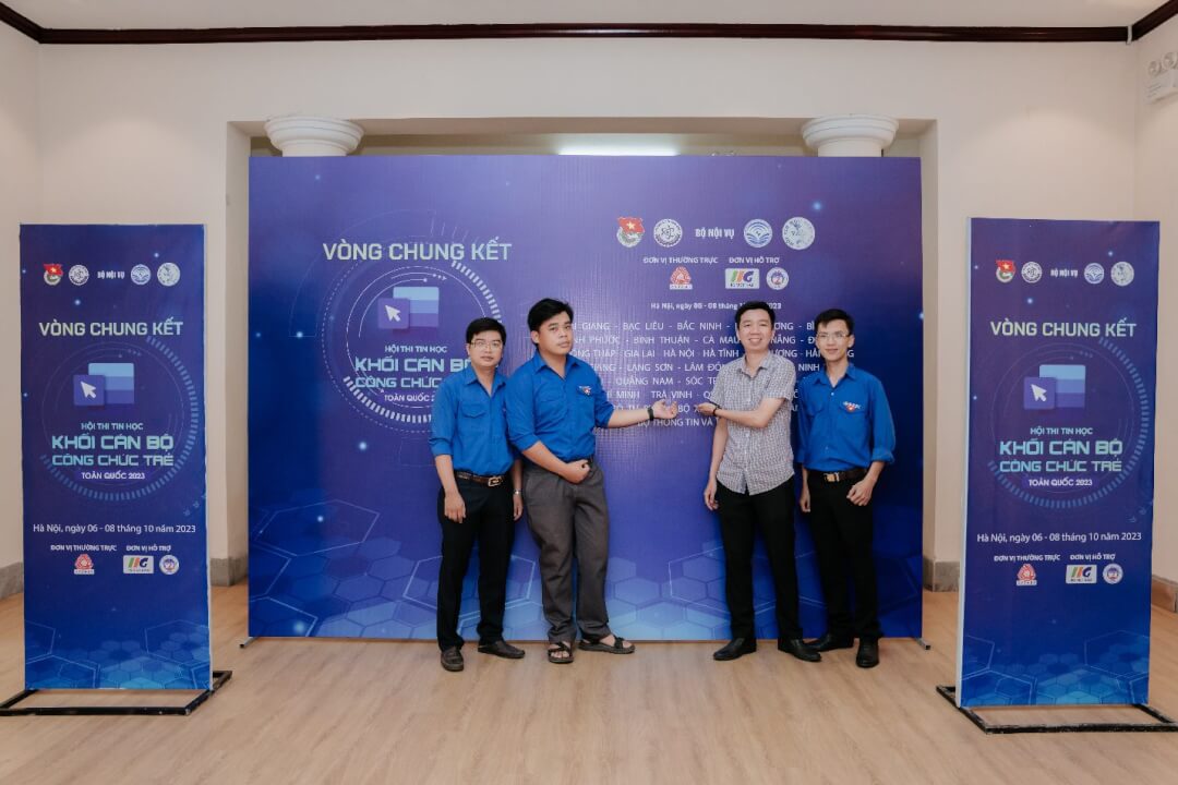 A group of people standing in front of a blue wall

Description automatically generated